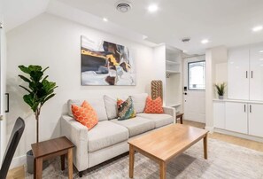 A modern living room with a sofa, coffee table, and a painting on the wall.