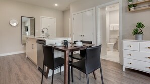 Une cuisine moderne avec une table et des chaises, un lave-vaisselle encastré et un meuble blanc.