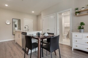 Une cuisine moderne avec une table et des chaises, un lave-vaisselle encastré et un meuble blanc.