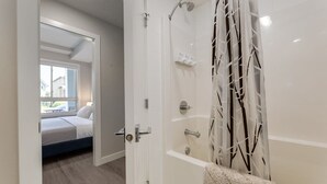 Une salle de bain moderne avec une douche à l’italienne, une baignoire et des toilettes apparentes.