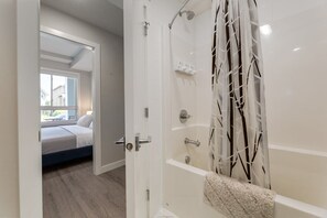Une salle de bain moderne avec une douche à l’italienne, une baignoire et des toilettes apparentes.