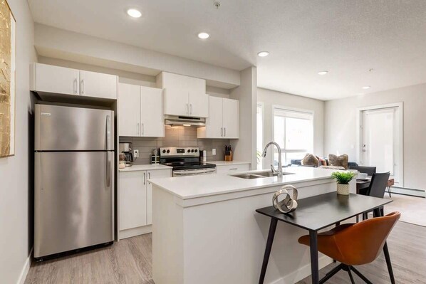 Prepare meals and socialize in this kitchen with a refrigerator, oven, and island with sink and seating area.