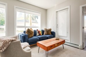 Relax in this inviting living room with a comfortable sofa, coffee table, and large windows.