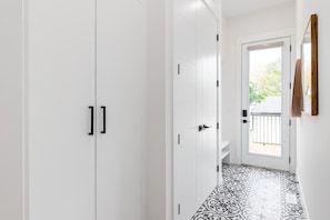 A hallway with white cabinets and a patterned floor leading to a door with a balcony view.