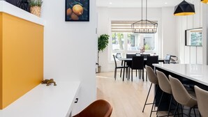 Eine moderne Küche mit weißem Arbeitsplatz, einer Essecke mit Tisch und Stühlen sowie einer hängenden Leuchte.