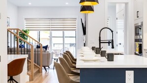 Uma cozinha moderna com ilha central, torneira preta e área de refeições com cadeiras e mesa.