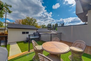 Een terras met een ronde tafel en rieten stoelen, een klein gebouw en een heldere lucht.