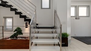 Un intérieur moderne avec un escalier, une plante en pot et un banc en bois.