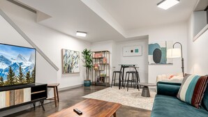 Un salon moderne comprenant un téléviseur, une bibliothèque, un coin repas et un canapé.