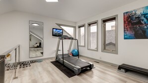 Une salle de sport à domicile équipée d’un tapis de course, d’un ballon d’exercice et de poids.