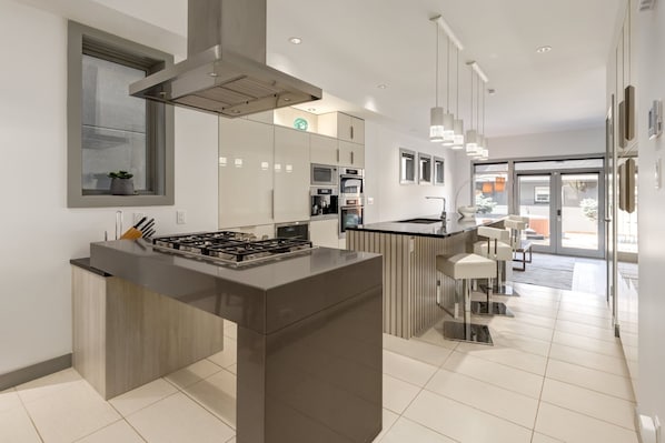 A modern kitchen with a central island, built-in appliances, and a view to the living area.