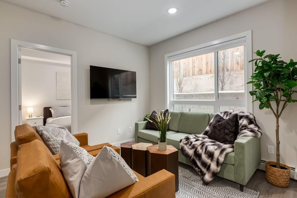 A modern living room with a sofa, a coffee table, and a TV mounted on the wall.
