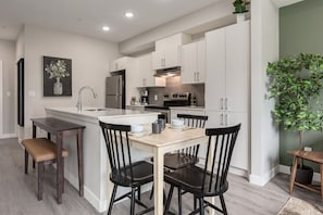 Une cuisine moderne avec des meubles blancs, un îlot central et des chaises noires.
