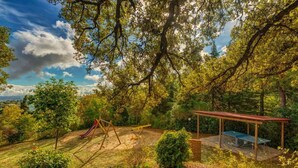 A park with a swing set, a slide, and a covered seating area. - Leccino 5 - Apartment with pool (Montaione)