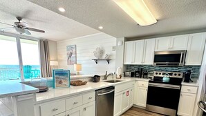 Una cocina moderna con armarios blancos, lavavajillas de acero inoxidable, estufa negra y un microondas.