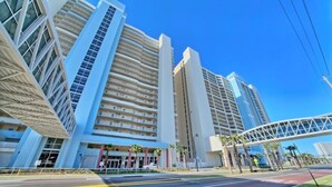 Un hotel moderno con varias edificaciones altas, un paseo techado y un cielo azul despejado.
