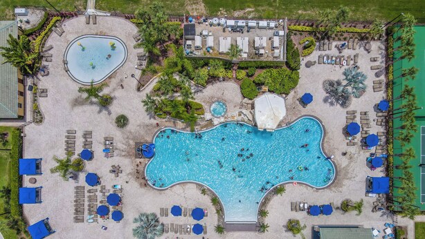 An aerial view of a resort with a large central pool, multiple smaller pools, and numerous sun loungers and umbrellas. - Amazing Townhouse Sleep10 Resort (Kissimmee)