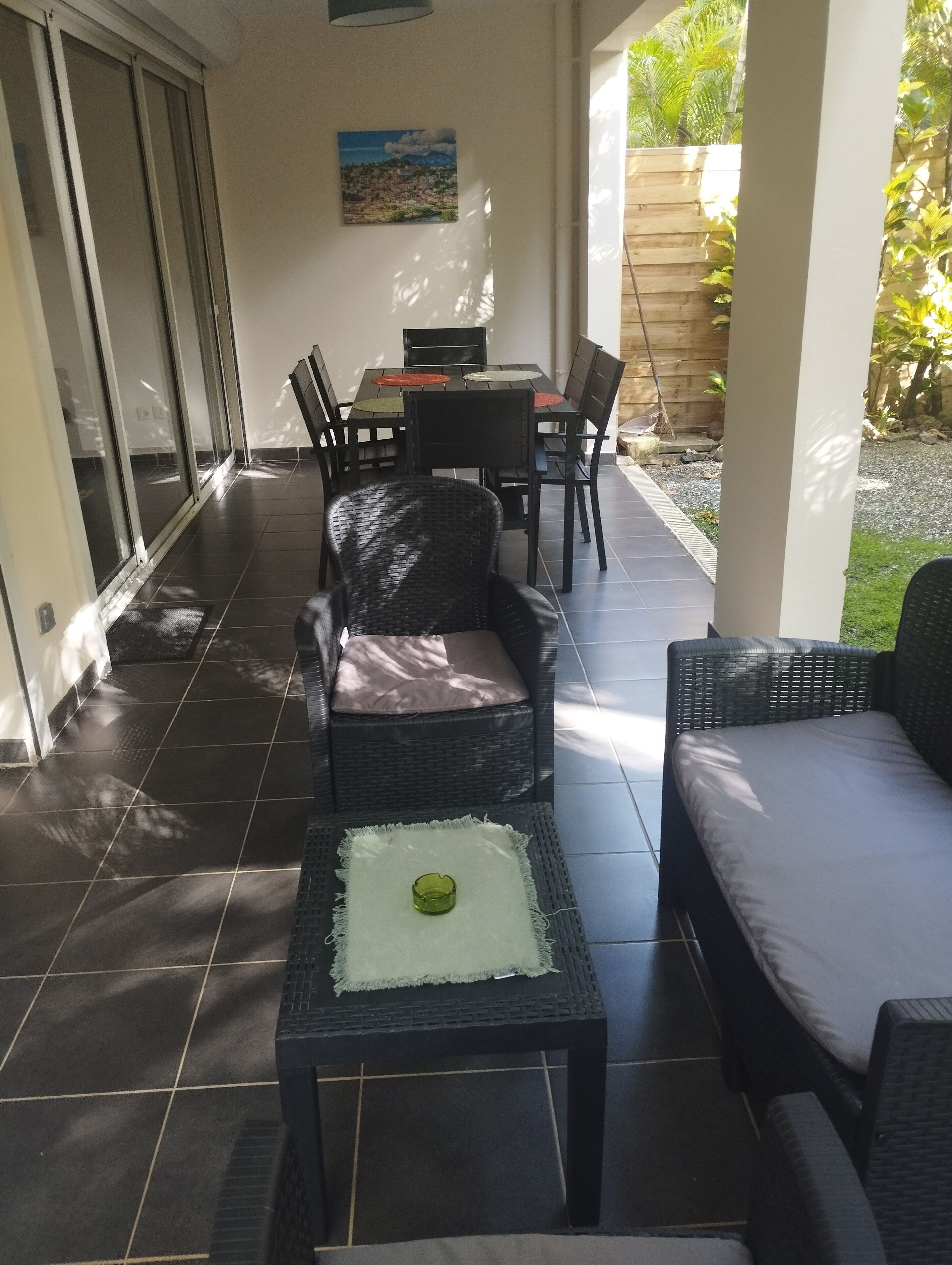 Un patio couvert aménagé avec des meubles en osier, une table et des chaises.