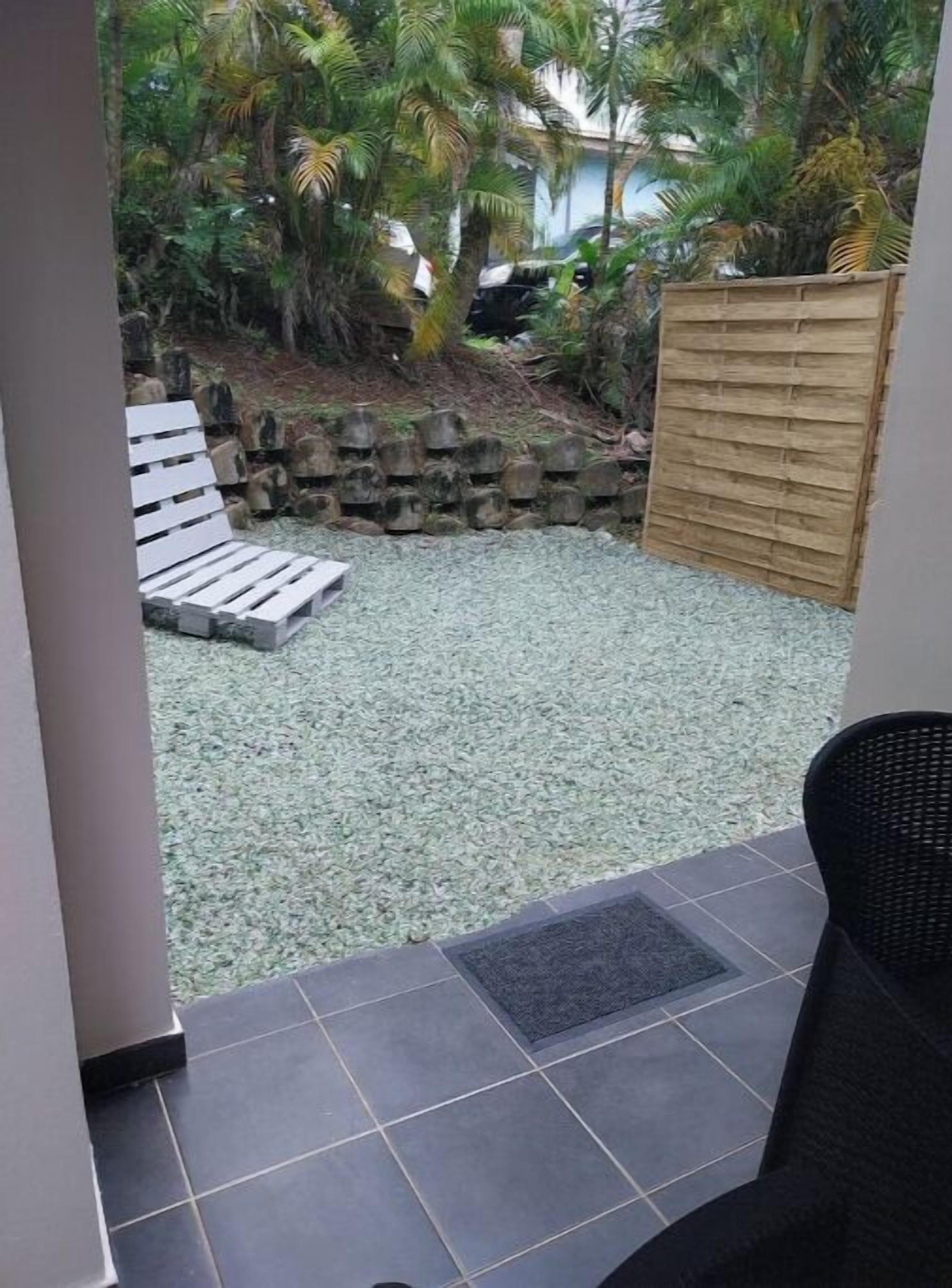 Een terras met een witte bank, een houten hek en een betegelde vloer.