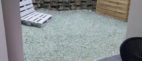 Un patio con un banco blanco, una valla de madera y piso de baldosas.