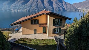 Una casa a due piani con tetto in tegole, un portico e vista su un lago e montagne.