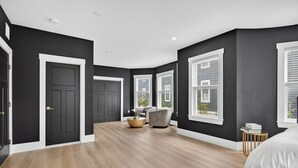 A spacious bedroom with a large bed, a wooden floor, and a view of the outdoors through a window. - Large victorian home 15 mins from downtown lots of local restaurants and bars  (Boston)