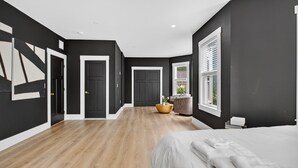 A modern bedroom with a large bed, a wooden floor, and a dark wall. - Large victorian home 15 mins from downtown lots of local restaurants and bars  (Boston)