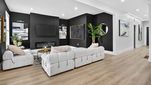 A modern living room with a white sectional sofa, a flat-screen TV, and a fireplace.