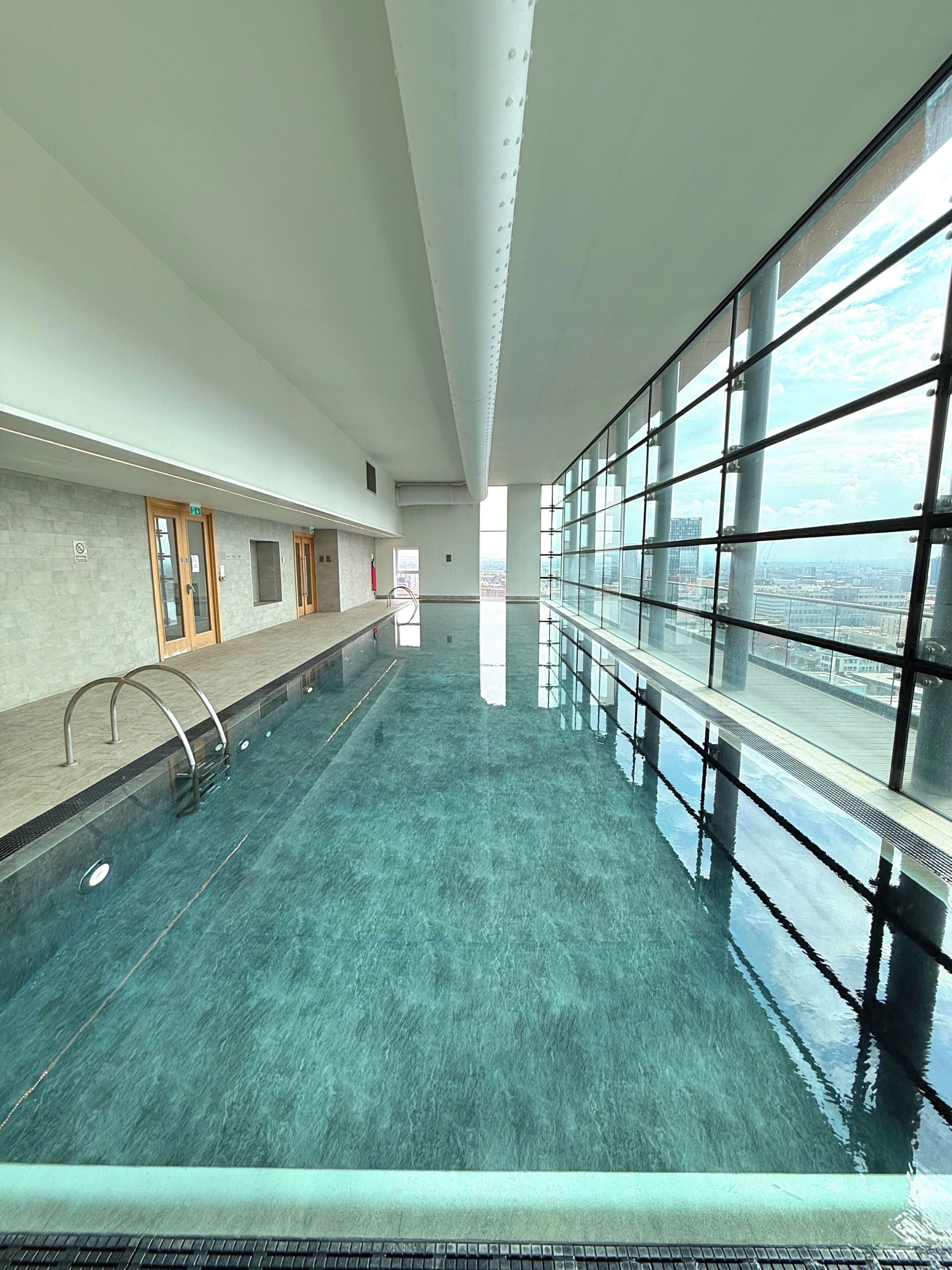 Ein Pool mit Blick auf die Stadt durch große Fenster.