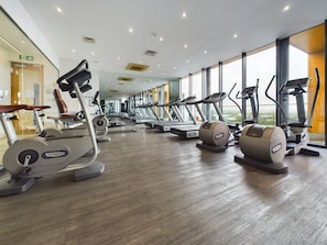 A modern gym with cardio machines, large windows, and a clean, spacious layout.