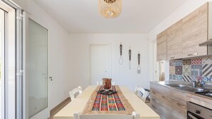 A modern kitchen with a dining table, chairs, and a patterned table runner.