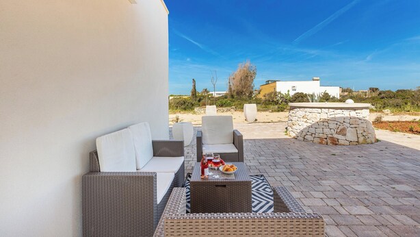 An outdoor seating area with wicker furniture and a table set with food and drinks.