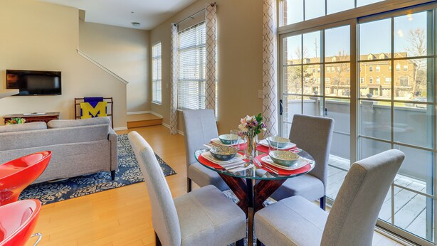 Una sala de estar moderna con comedor, ventanas amplias y una escalera.