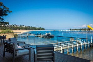 A deck with chairs overlooking a marina with boats and a clear view of the coastline.