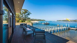 A deck with outdoor seating overlooking a marina and water. - SouthWind (Merimbula)