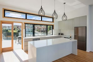 A modern kitchen with a large island, stainless steel appliances, and pendant lighting.