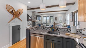 A modern kitchen with a central island, stainless steel appliances, and a wooden ceiling. - Bearfoot Lodge (Waterville Valley)