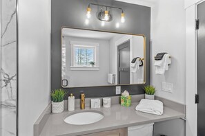 A modern bathroom with a large mirror, a sink, and a towel rack. - Bearfoot Lodge (Waterville Valley)
