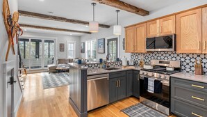 A modern kitchen with dark cabinets, stainless steel appliances, and a wooden ceiling. - Bearfoot Lodge (Waterville Valley)