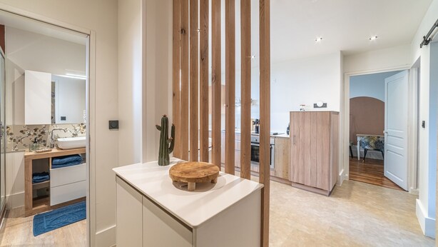 A modern bathroom with a wooden divider, a sink with a mirror, and a blue towel on the floor. - Le Jungle - Appt pour 6 avec parking privé (Paray-le-Monial)