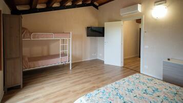 Ein Zimmer mit einem Etagenbett, Holzboden, einer Tür und einer Wand-Klimaanlage.