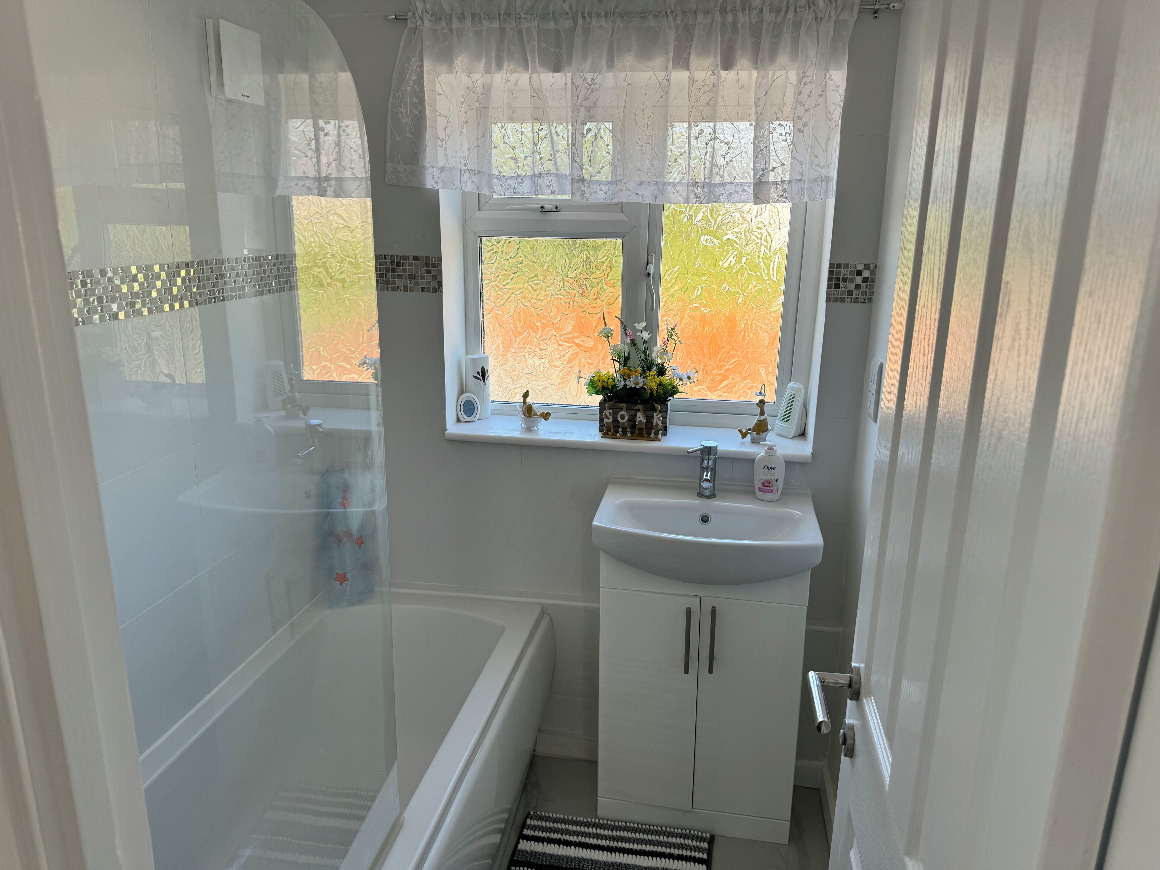 A bathroom with a bathtub, a sink, a window with a view, and a shower area.
