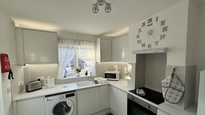 Eine moderne Küche mit Waschmaschine, Mikrowelle, Backofen und einem Fenster mit Vorhängen.