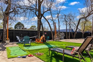 A backyard with artificial grass, outdoor furniture, and a wooden fence.