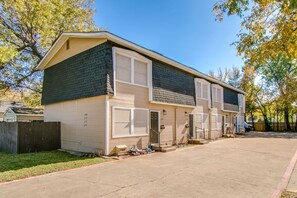 A two-story residential building with a garage, a fenced yard, and a clear sky.