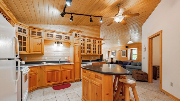 Une cuisine spacieuse avec des meubles en bois, un grand îlot central et un ventilateur de plafond.