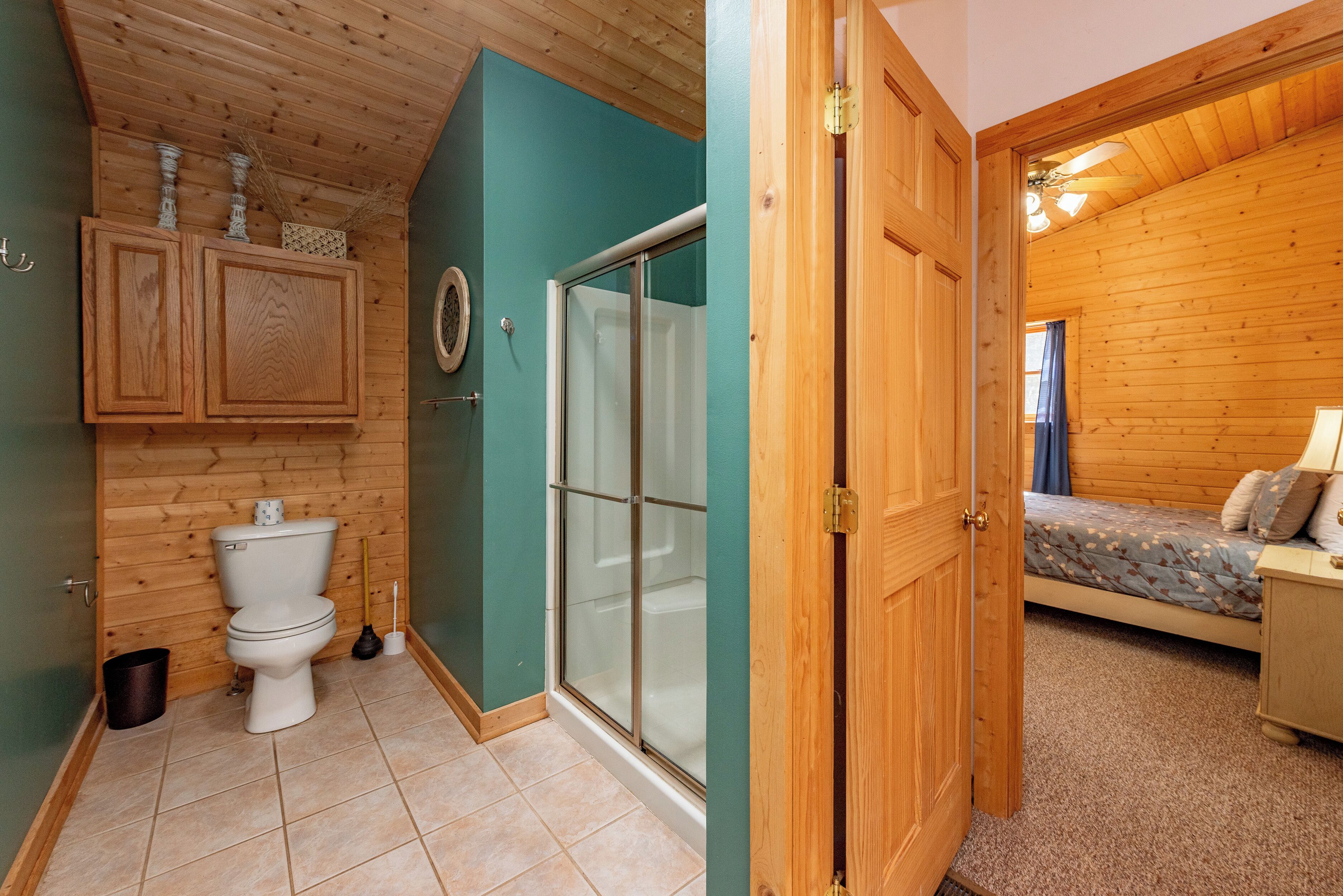Interior de madera con un baño que incluye inodoro, ducha y armarios de madera.