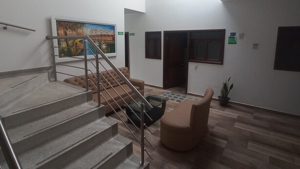 A modern lobby with a staircase, a sofa, a coffee table, and a painting on the wall.