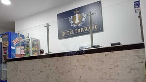 A reception desk with a sign reading "HOTEL TORRADO" and a logo above it.