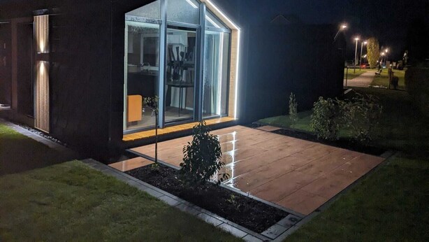 A modern house with large glass windows and a well-lit outdoor area.